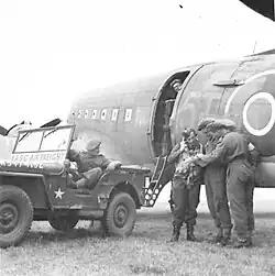 F.0. Clarkson, G.T., R.A.F., 233 Sqd. of Ellesmere Port, hands his load chit to Spl.Moss, R.A.S.C., of Croydon, who is the Air Freight reception clerk, on landing from U.K. with compo rations, Sep 20, 1944.