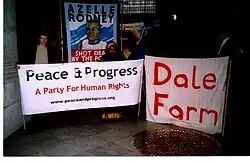Photo showing people displaying large banners with the words "Peace & Progress, a Party For Human Rights" and "Dale Farm" with a banner of Azelle Rodney in the background.