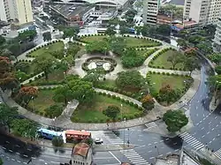 A circular green space in a city with eight paths that lead to the center of the circle.