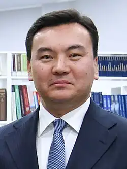 Headshot of Rauan Kenzhekhanuly in an office. He is a middle-aged man wearing a suit, half-smiling.