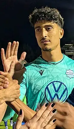 Man with his right hand raised in front of people giving dab