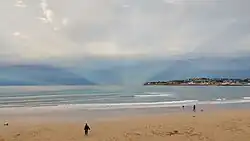 Atmospheric effect of anticrepuscular rays opposite the sunset in the bay of San Lorenzo, Gijón, Spain