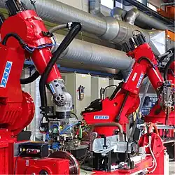 2 large industrial robots process material in a welding cell