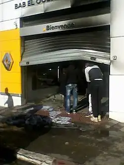 Broken shop curtain with people looking inside.