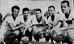 Black and while photo of a group of five Brazilian football player crouching together.