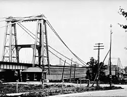 Towers, made of steel beams, hold up the cables that suspend a bridge.
