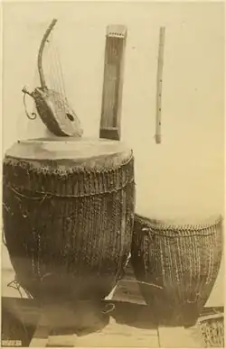 South Sudan or Northern Uganda. Acholi people, type D trough zither (center back), arched harp (left), unnamed flute (right). Circa 1880. The zither is a nanga or possibly kinanda.