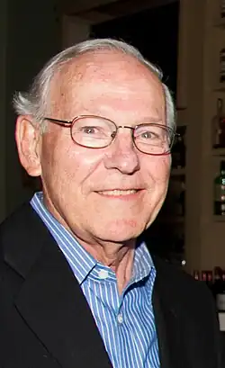 Tightly cropped photo of a smiling man with gray hair and glasses