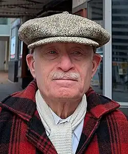 Head and shoulders photo of Richard Striner wearing a red and black plaid coat, white scarf, and mottled cap