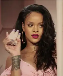Rihanna smiling, holding Fenty products