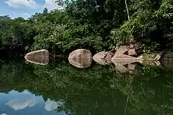 Large boulders reflect on the water of the river