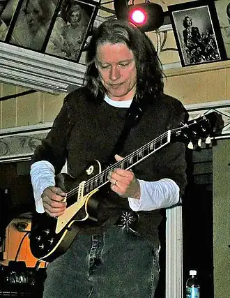 Robben Ford standing on a scene in february 2007 playing on a metallic Les Paul-style cut-away guitar.