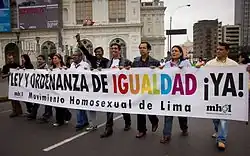 Group of people at a pride parade holding a banner