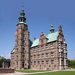 Castle with turrets and spires and walled enclosure, on the tip of a narrow peninsula.