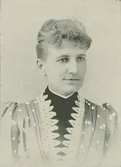 19th-century B&W portrait photo of a woman with her hair in an up-do, wearing a dark, fitted blouse.