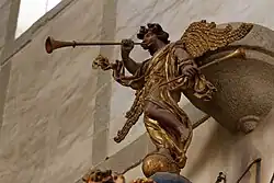 The "renommé" at the summit of the pulpit canopy plays a trumpet, her foot resting on a globe