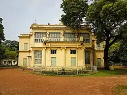 Historic ashram building with verandas in a shaded grove