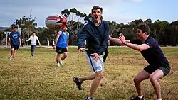 Scott Minto passing a football in a park