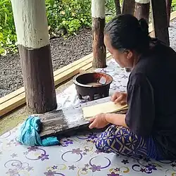 Using water and a shell to scrape and soften the bark