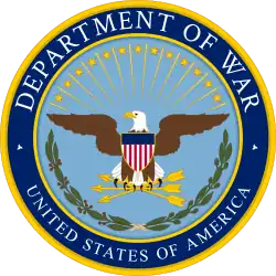 Alternate seal of the United States Department of Defense, depicting an American Eagle holding three arrows, superimposed by the shield adorned with the design of the American flag. Below is the green wreath. Rind reads "DEPARTMENT OF WAR" and "UNITED STATES OF AMERICA".