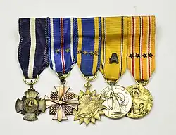 Five military medals suspended from ribbons arranged in a horizontal row