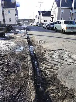 Setts visible beneath cracked asphalt in New Bedford, Massachusetts, United States.