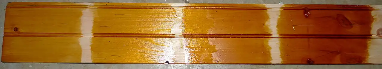 "Quick and dirty" example of a pine board coated with 1–5 coats of Dewaxed Dark shellac (a darker version of traditional orange shellac)