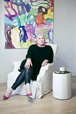 Seated portrait of Sherry Chris in front of an abstract painting.