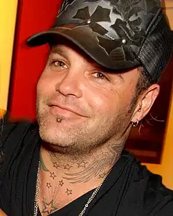 close-up of Binzer wearing a dark shirt and patterned baseball cap and smiling at camera