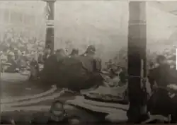 Black and white photography of sumo judges squatting at the side of the ring to discuss a call