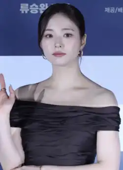 Shin wearing a gray off shoulder dress and posing for the camera