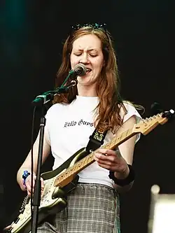 Sidney Gish on stage with a guitar and microphone
