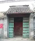 A folding security gate has been installed outside the once-elegant gate of the siheyuan