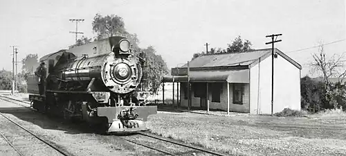 A Silverton Tramway Company W class steam locomotive, almost identical to the Western Australian Government Railways W class, adjacent to a corrugated iron Burns station building