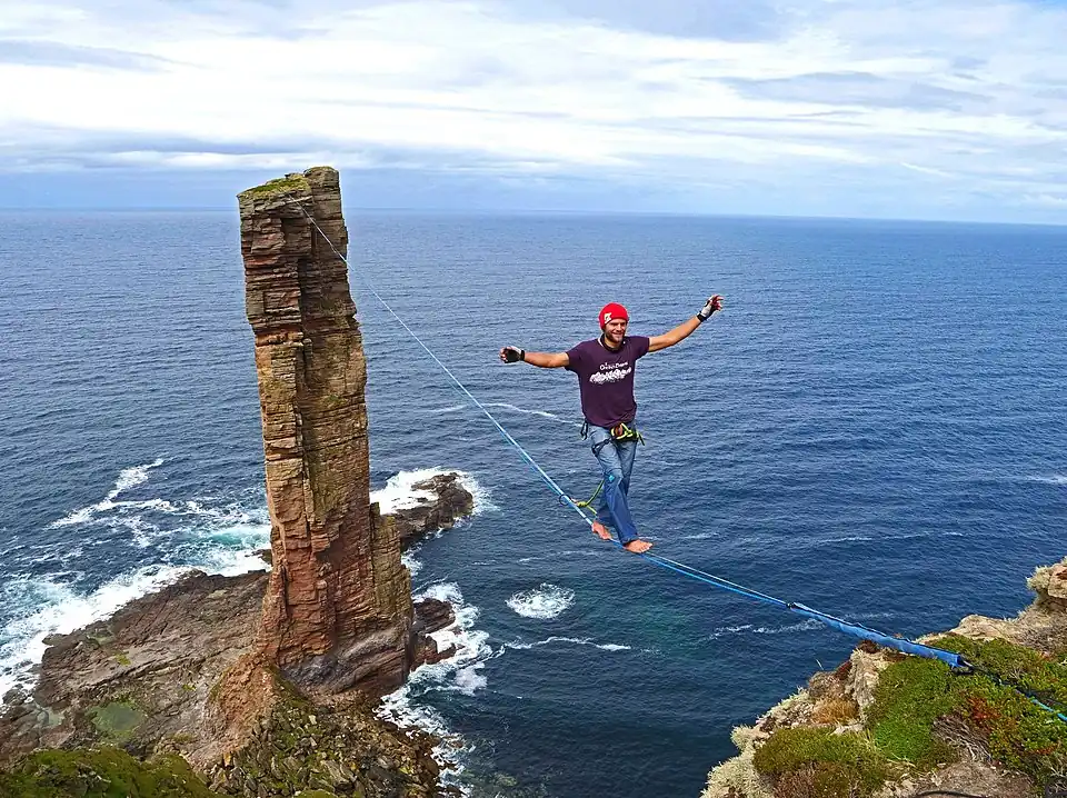 A walker slacklining at the Old Man of Hoy