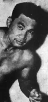 A young shirtless Asian man in a loosely-held fighting pose