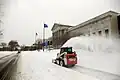 Skid loader clearing snow with snow blower attachment