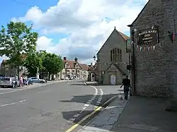 Street scene with houses and pub on the right and trees on the left.