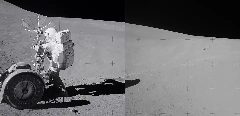Spur crater in background, with astronaut David Scott at left next to rover. The breccia boulder is at right in the distance.