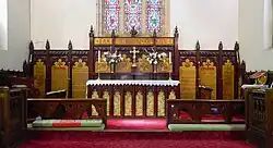 Panoramic photograph of the hand carved and painted cedar woodwork in the St John's chancel, with red carpet