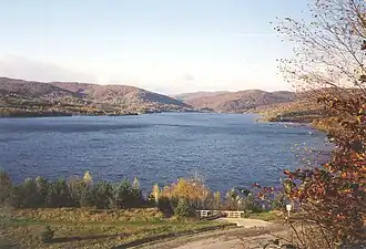 Deep blue lake surrounded by dense, dark evergreen forest slopes