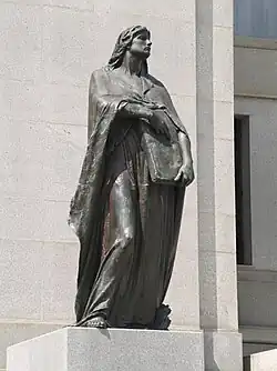 Photo of a statue of a robed woman holding a book