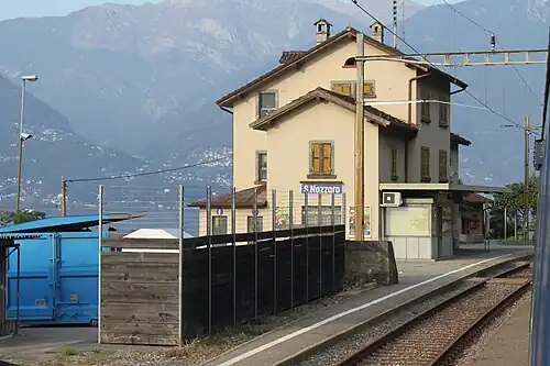 Three-story building with gabled roof next to double-track railway line