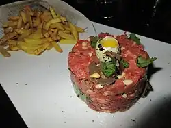 Raw beef shaped into a disk and garnished with a quail egg