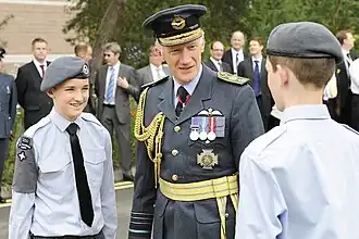 Cadets of the British Armed Forces wear a brassard on the right arm to display unit identity and merit badges.