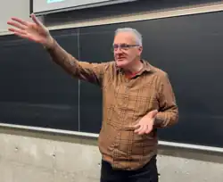 Stephen Gaetz stands in front of a blackboard in a university lecture hall.