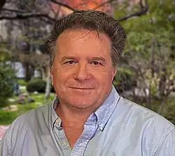close-up image of Steven Sachs wearing a light blue shirt, looking directly at camera with slight smile
