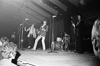 Black and white photo of the five members of the Rolling Stones performing on stage