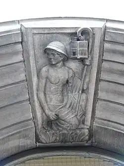 Stone statue of a miner holding a canary in a cage