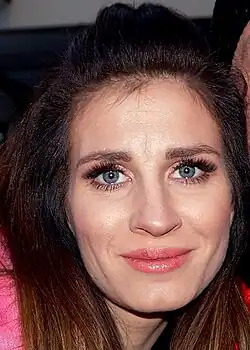 Sylwia Grzeszczak posing for a photo. Her face is illuminated by the light of a flash.